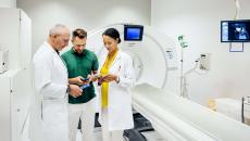 Healthcare workers looking at phones next to MRI machine