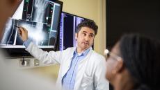 Radiologist points to image on screen during a consultation with fellow clinicians